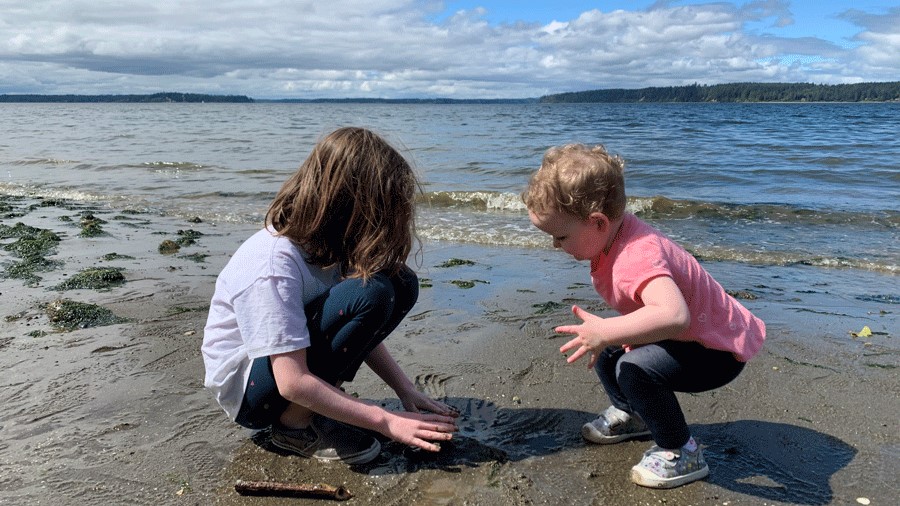 two kids explore the beach at Penrose Point State park a best family campground in Washington state parks