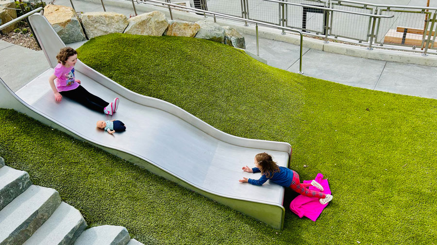 two girls playing on a slide in Melanie's Park in Tacoma