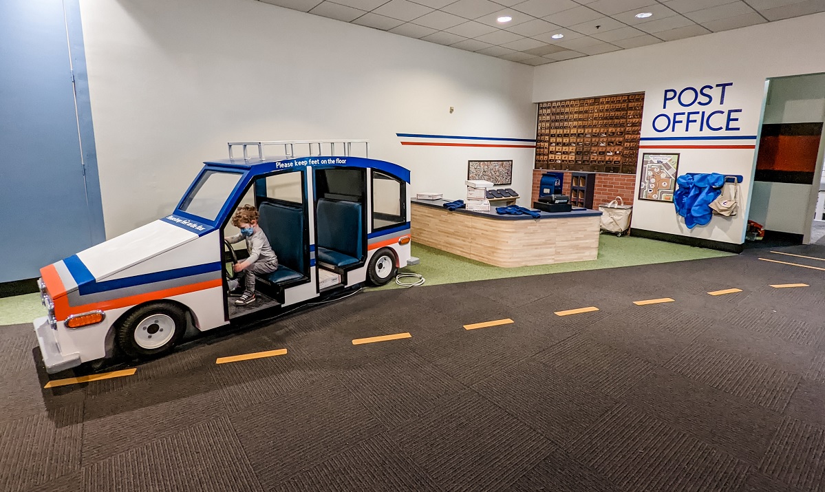 Boy driving toy postal carrier car in recently reopened Seattle Children's Museum at Seattle Center