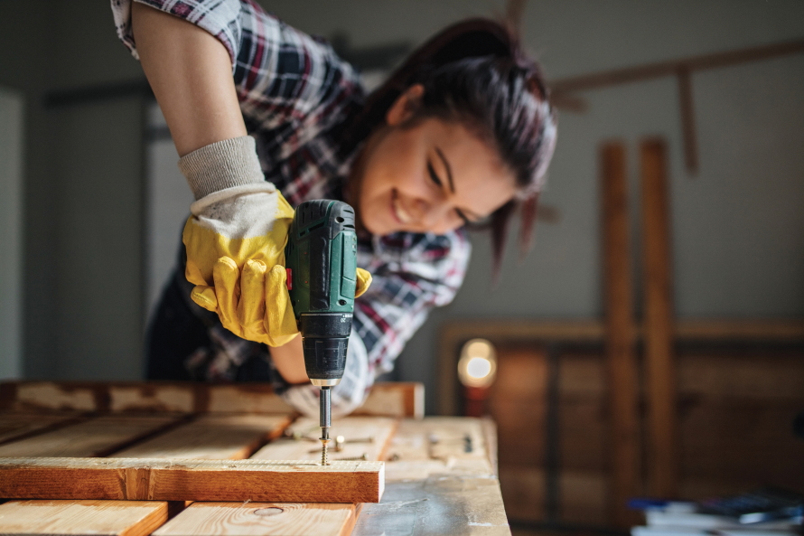Young woman screwing two pieces of wood together