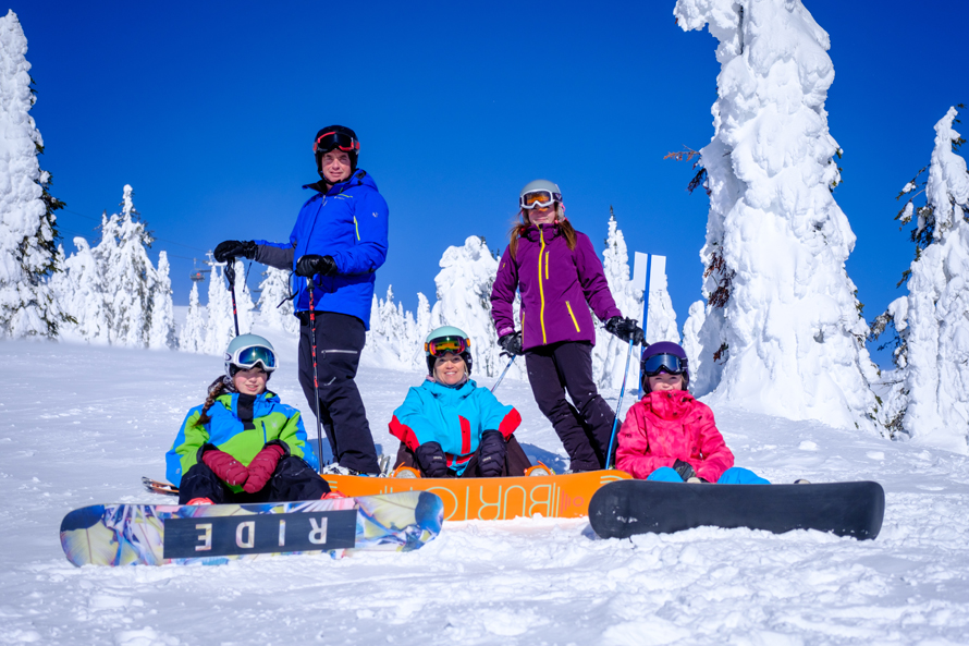 kids sitting in the snow with snowboards