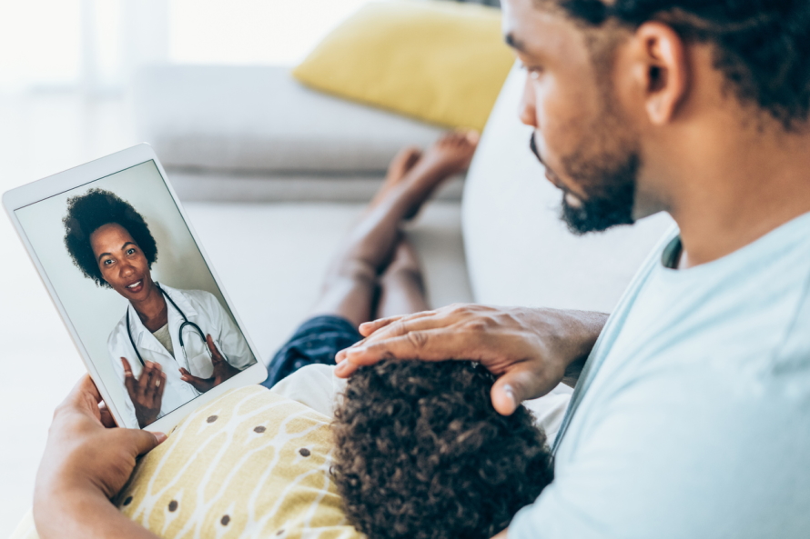 Dad with a sick child in his lap having telemedicine appointment with doctor