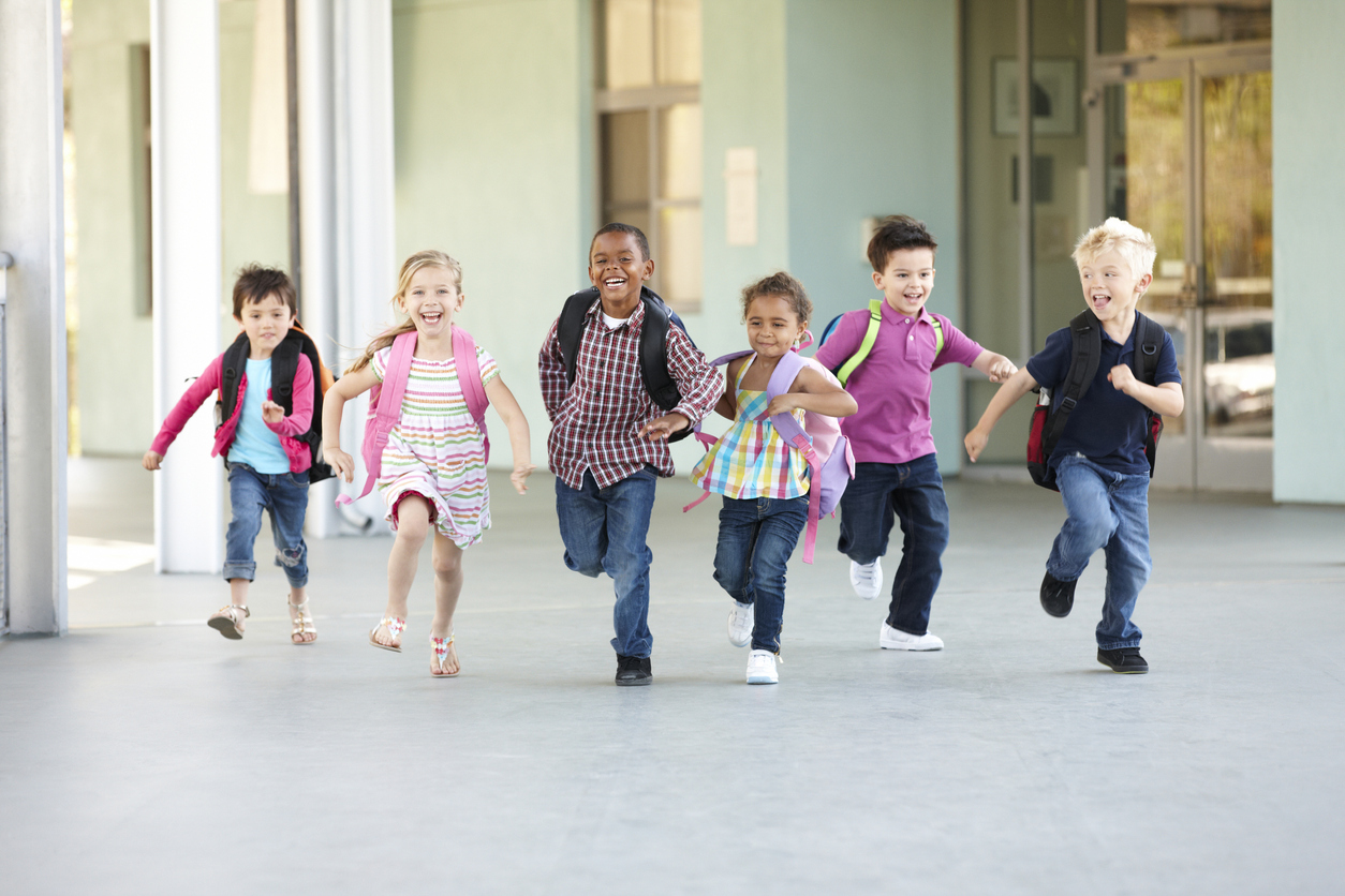 Group of elementary school children running out of a school building