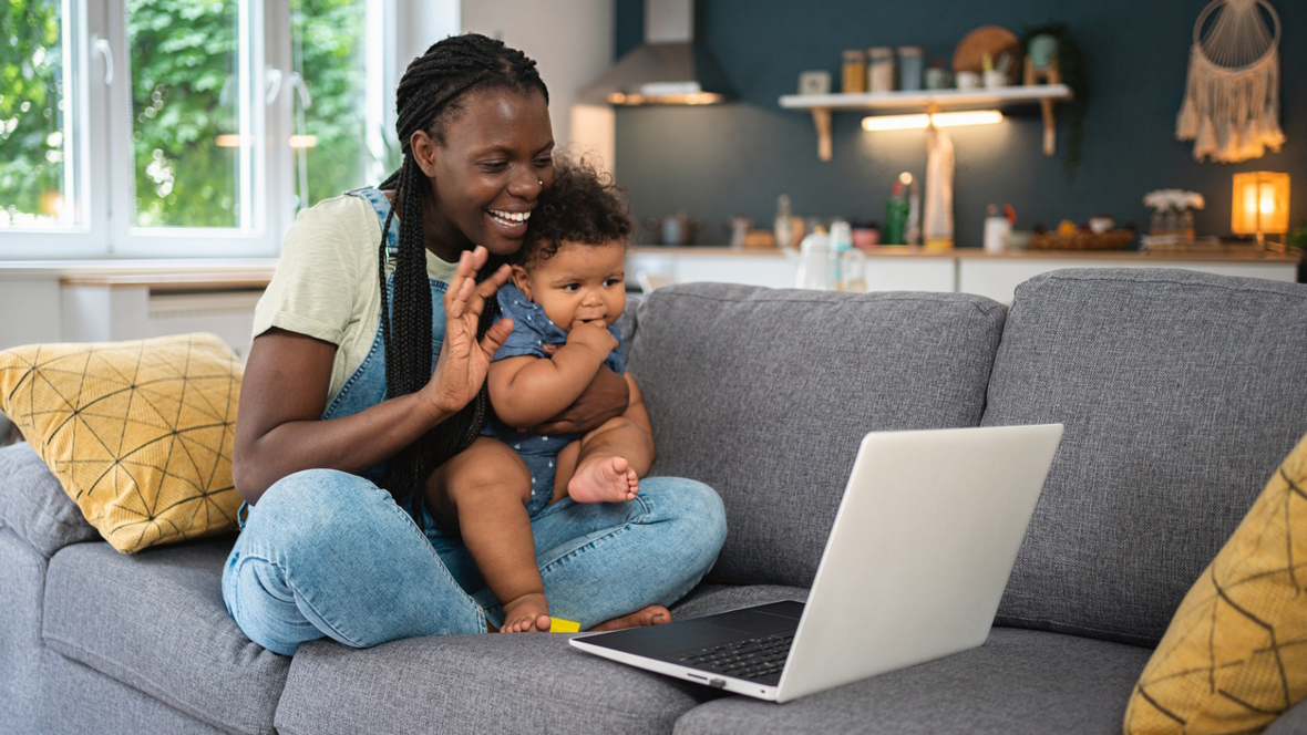 mom holding a baby waving to a computer call finding community online