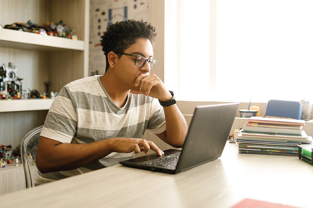 teenage boy with glasses working on a laptop