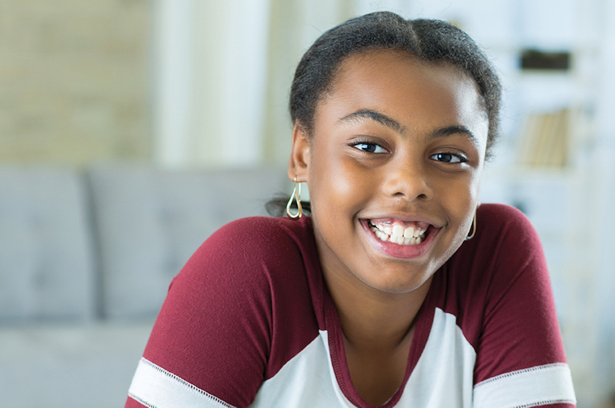 girl sitting indoors smiling at the camera
