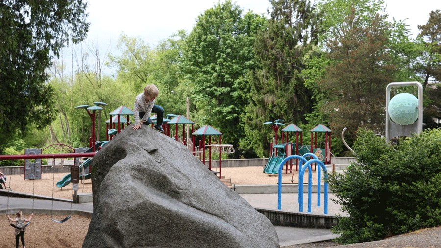 kid climbing a huge rock at city park in Edmonds, a fun destination for families