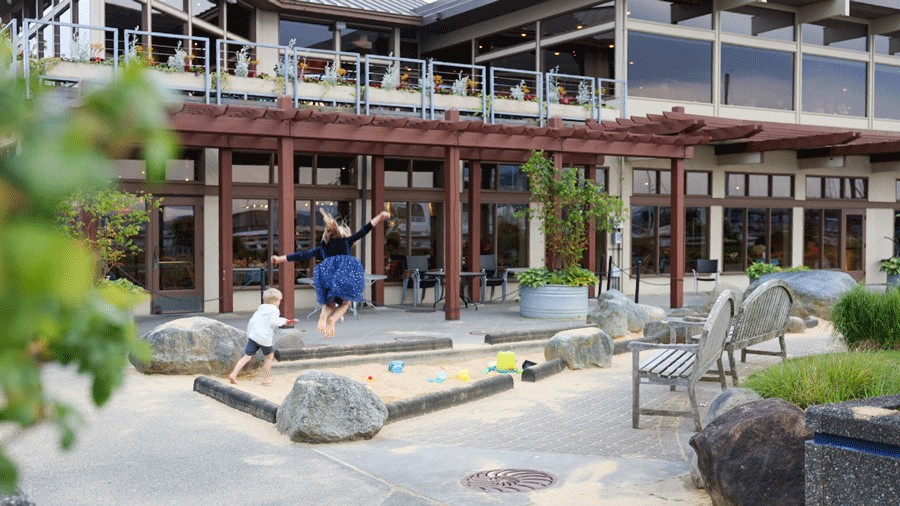 kids jumping into the sand play area at Anthony's Homeport Edmonds, a family-friendly restaurant with a patio