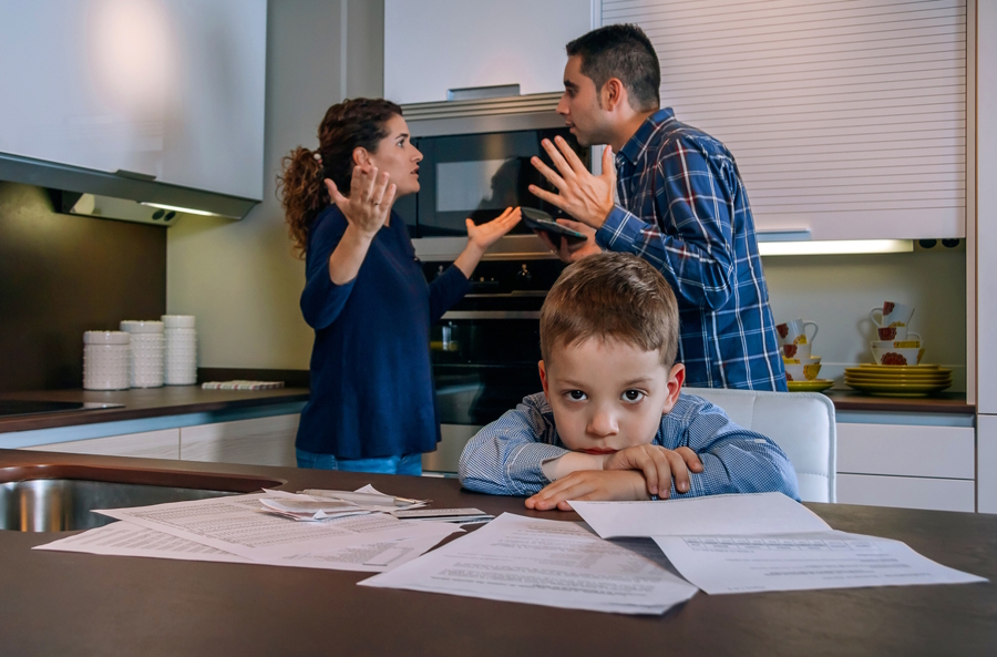 parents arguing about money in front of son who looks sad