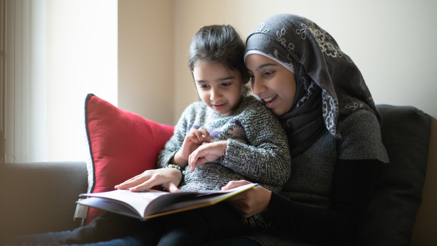 Two Muslim girls reading a book together