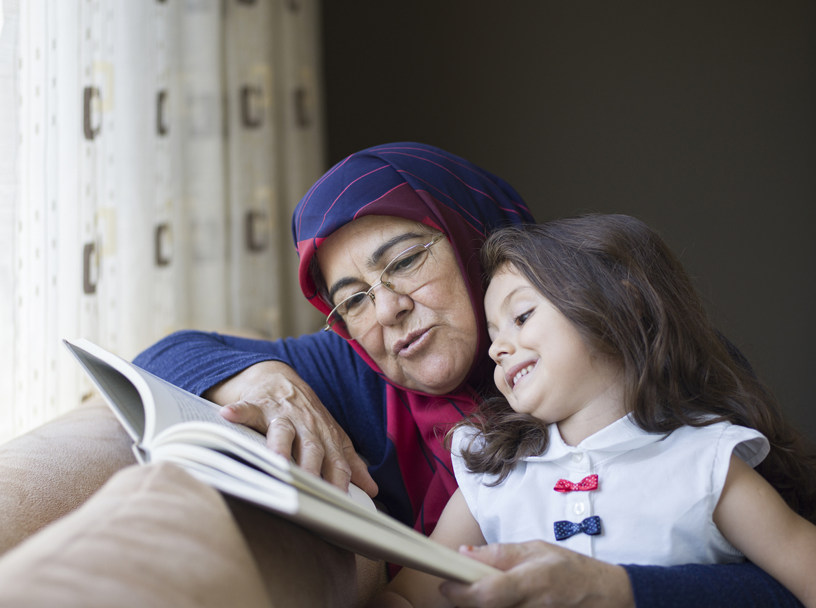 grandmother and grand daughter reading together on the couch