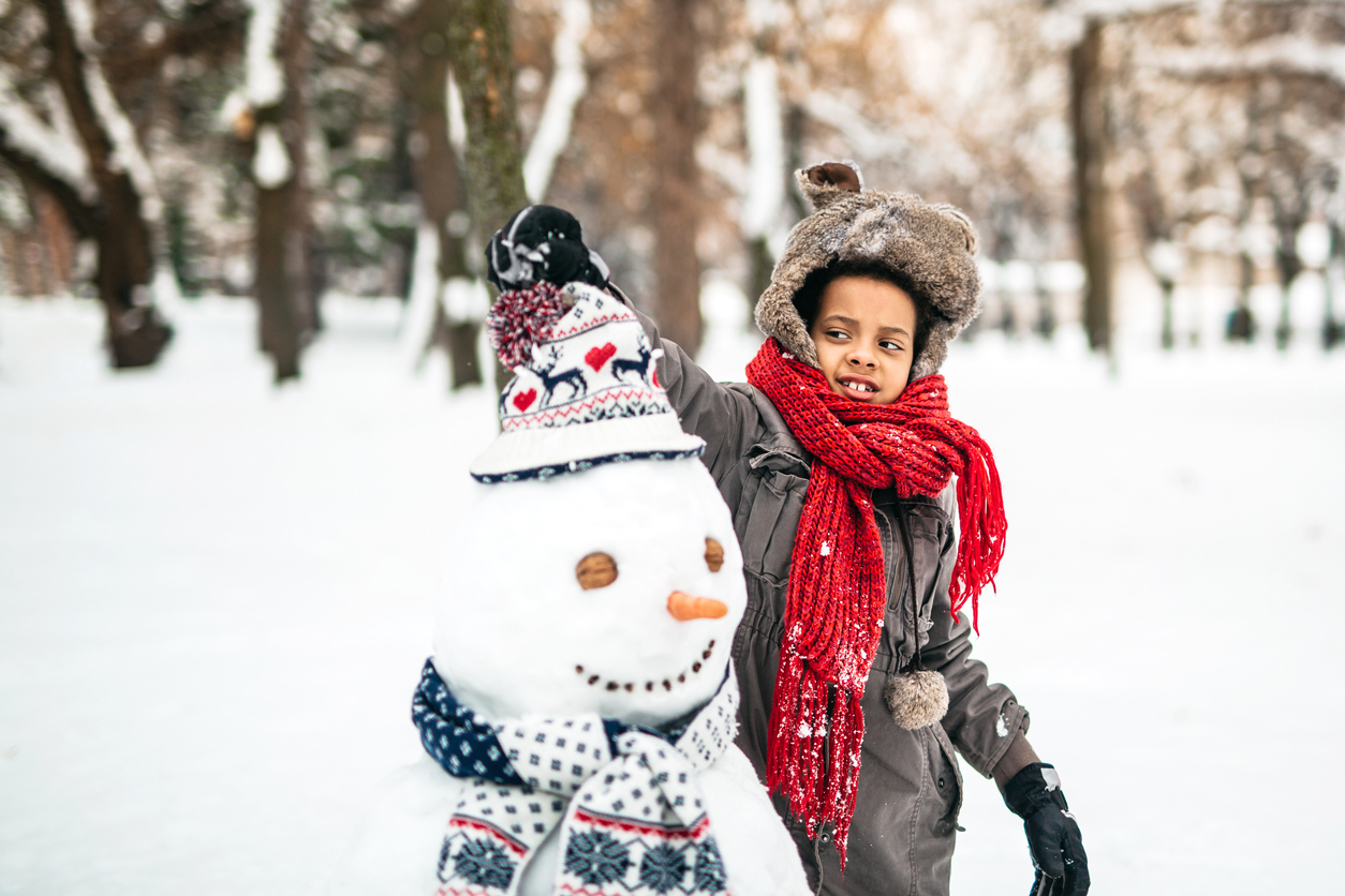 Young girl enjoying the winter by making a snowman