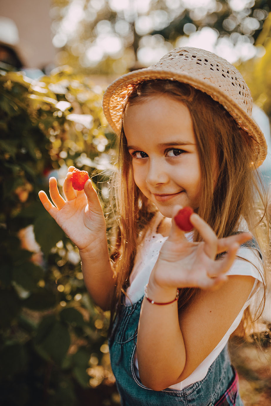 Girl wearing a hat picking raspberries