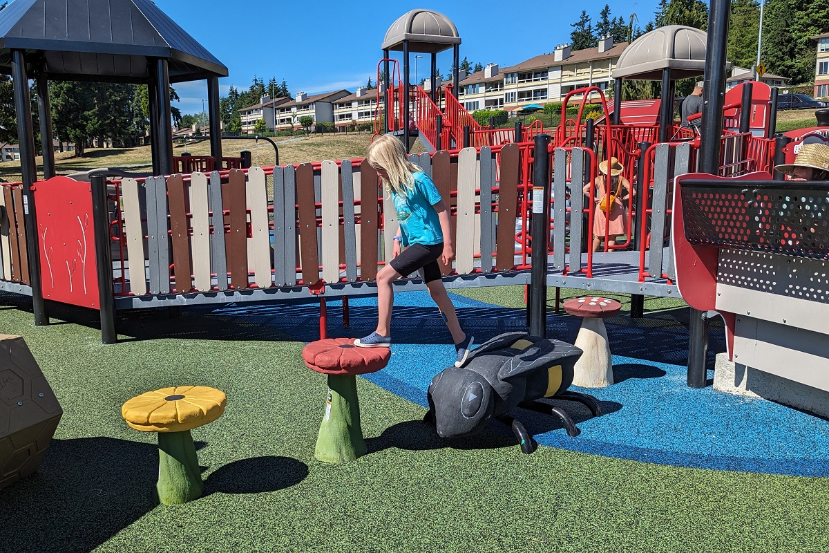A girl plays on balance steps in the shape of flowers and a bee at the new playground at Ballinger Park