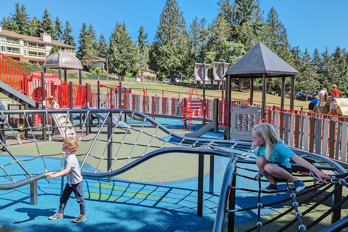 A girl balances on an undulating cargo climber at the new Hazel Miller playground at Mountlake Terrace's Ballinger Park