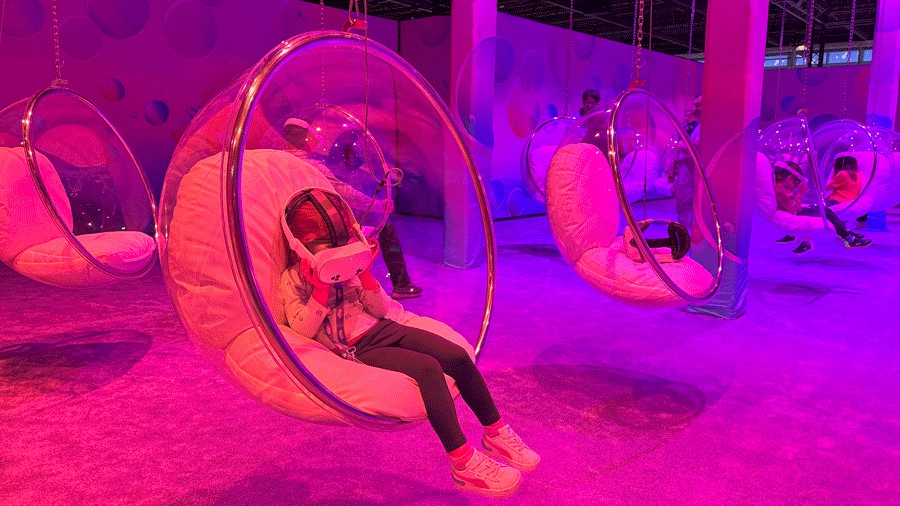 Young girl with VR headset, immersed in a bubble-filled world, sitting on a bubble chair