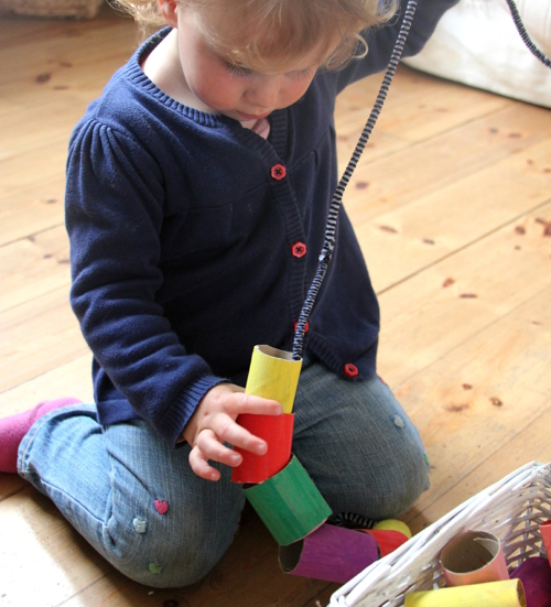 Toddler threading giant carboard beads on a thin rope