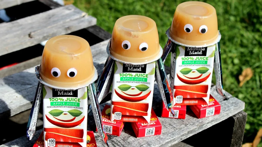 Snack robots made out of apple sauce containers, juicebox and 2 boxes of raisins