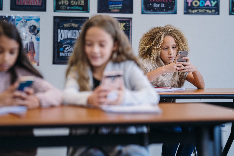 Kids sitting in their classroom at school not listening, looking at their cell phones