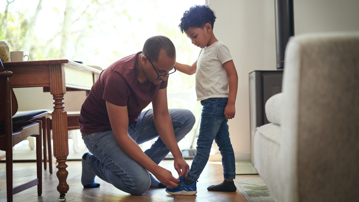 A dad helps his son try on shoes looking for the right size, one that fits