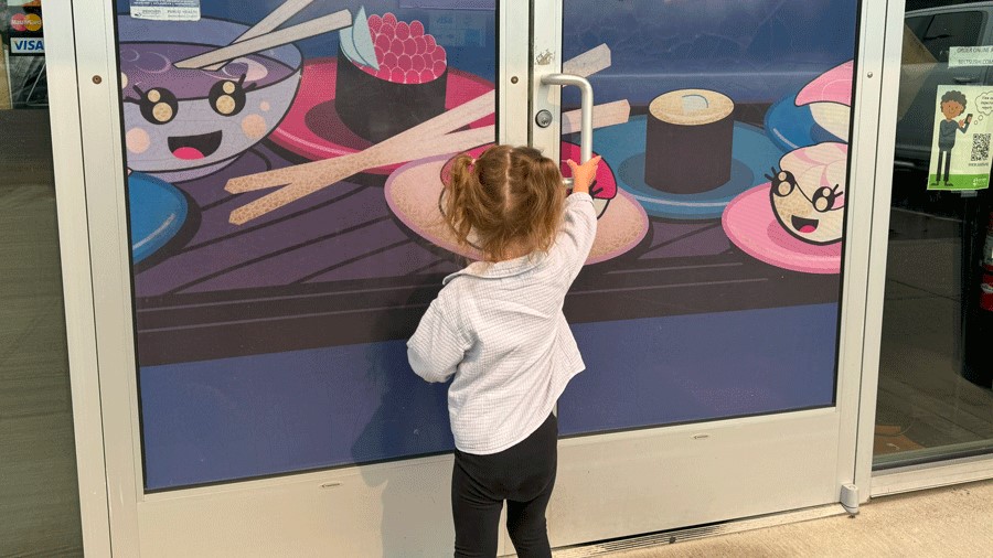 Young girl opening the doors to a sushi conveyor belt restaurant near Seattle