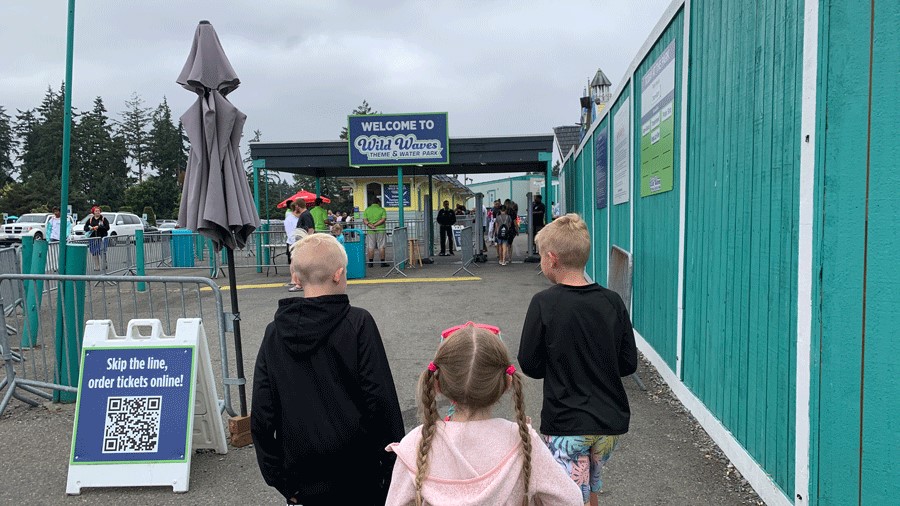 Three kids walking into the entrance of Wild Waves Theme and Water Park near Seattle