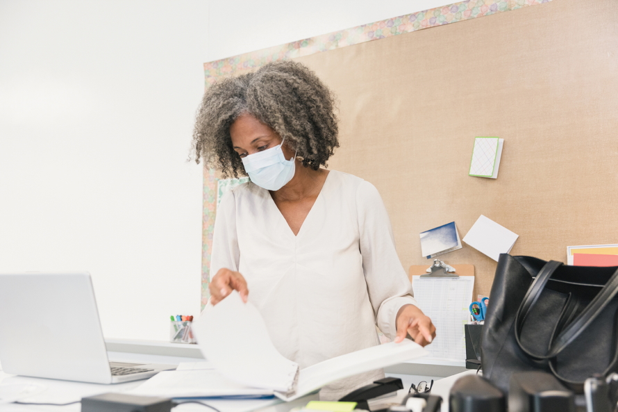 Woman looking through a notebook on a messy desk