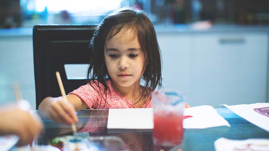 girl painting at dining room table