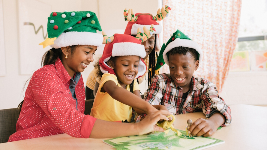 kids wearing holiday hats and doing a winter craft activity