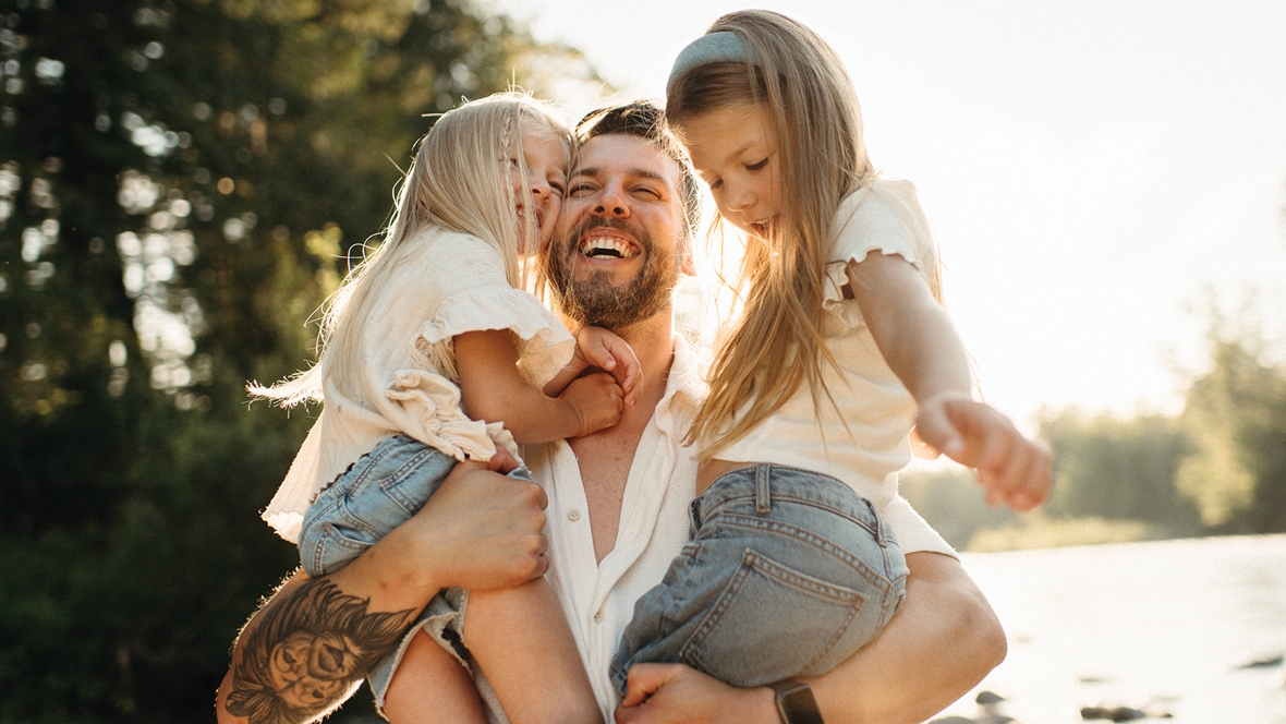 dad holding two daughters smiling and happy