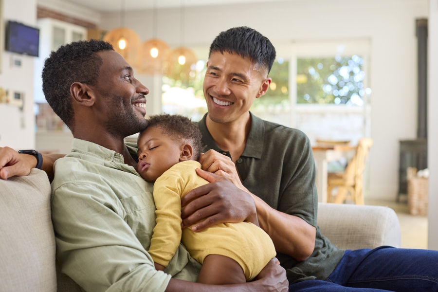 two dads sitting together with baby on Father’s Day
