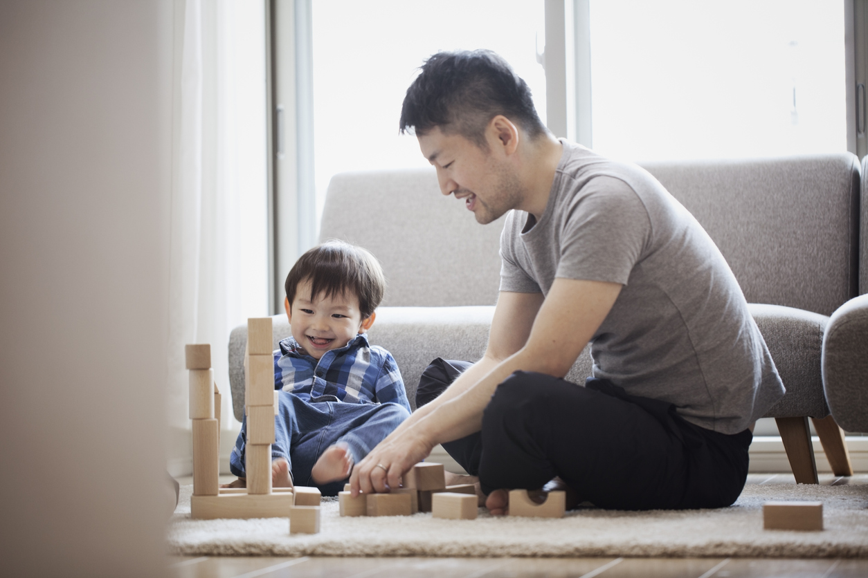 father and son playing with wood blocks on the living room floor