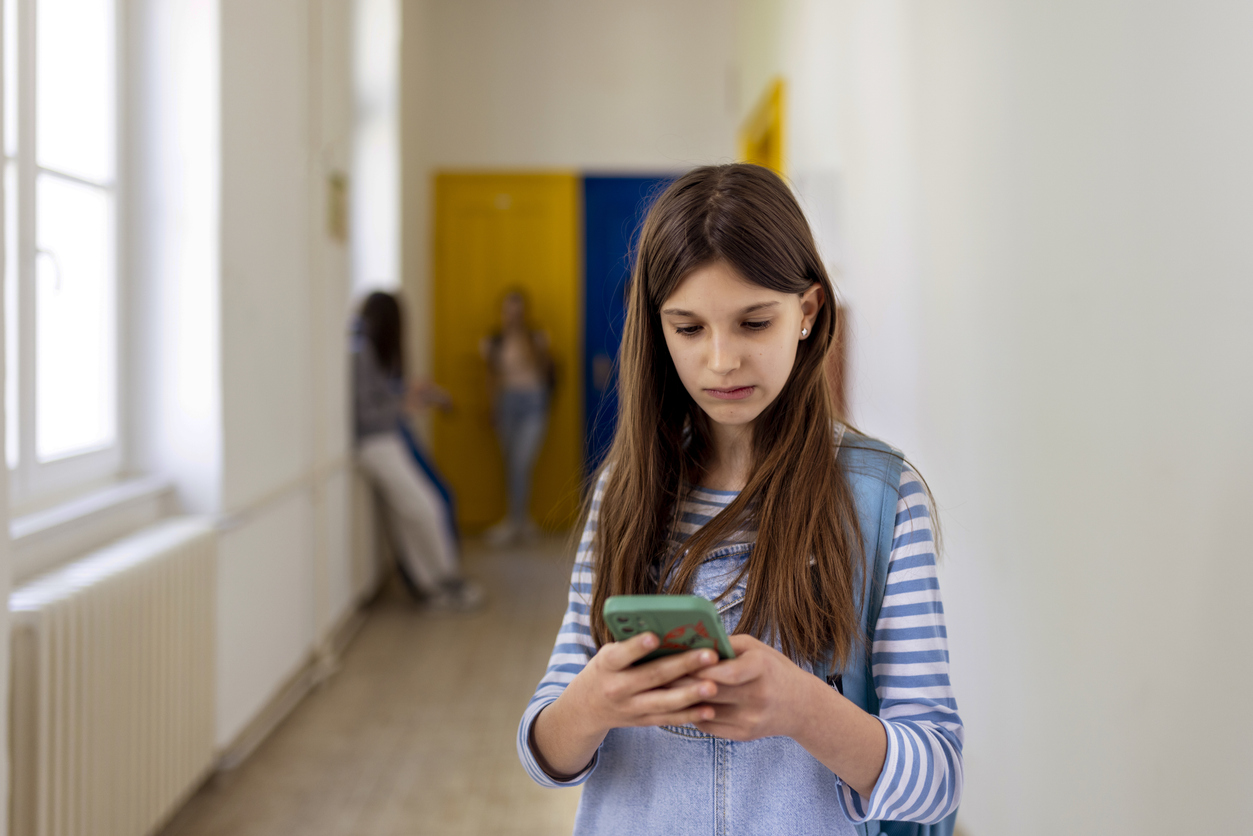 a student looks at a cell phone at school and seems unhappy