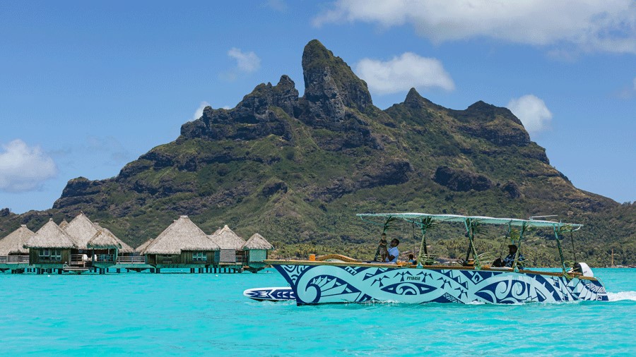 Lagoon Service Bora Bora boat in the water passing bungalows