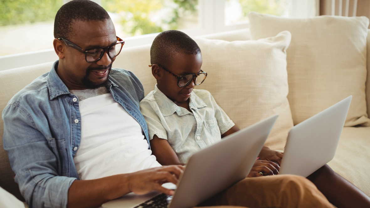 father and son sitting on a couch typing on laptops during NaNoWriMo