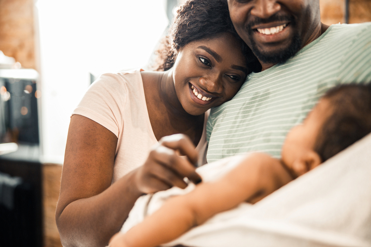 black mother and father smiling at their new baby