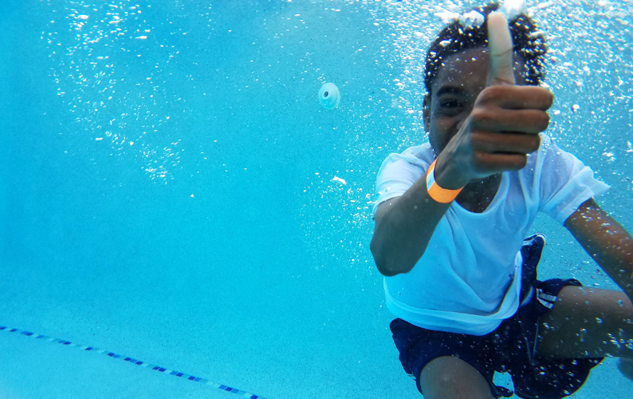 boy underwater in the pool giving a thumbs up