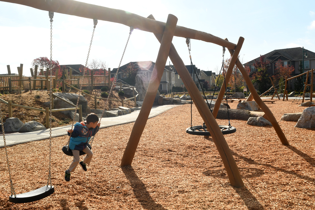 Boy on swings at Mill Creek's Exploration Playground fun parks around the Seattle region