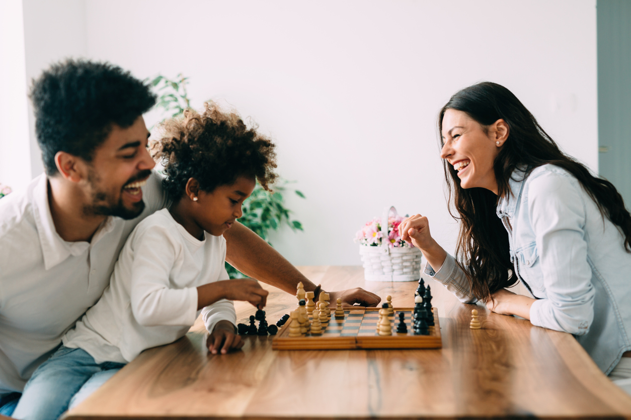 family playing chess at the kitchen table