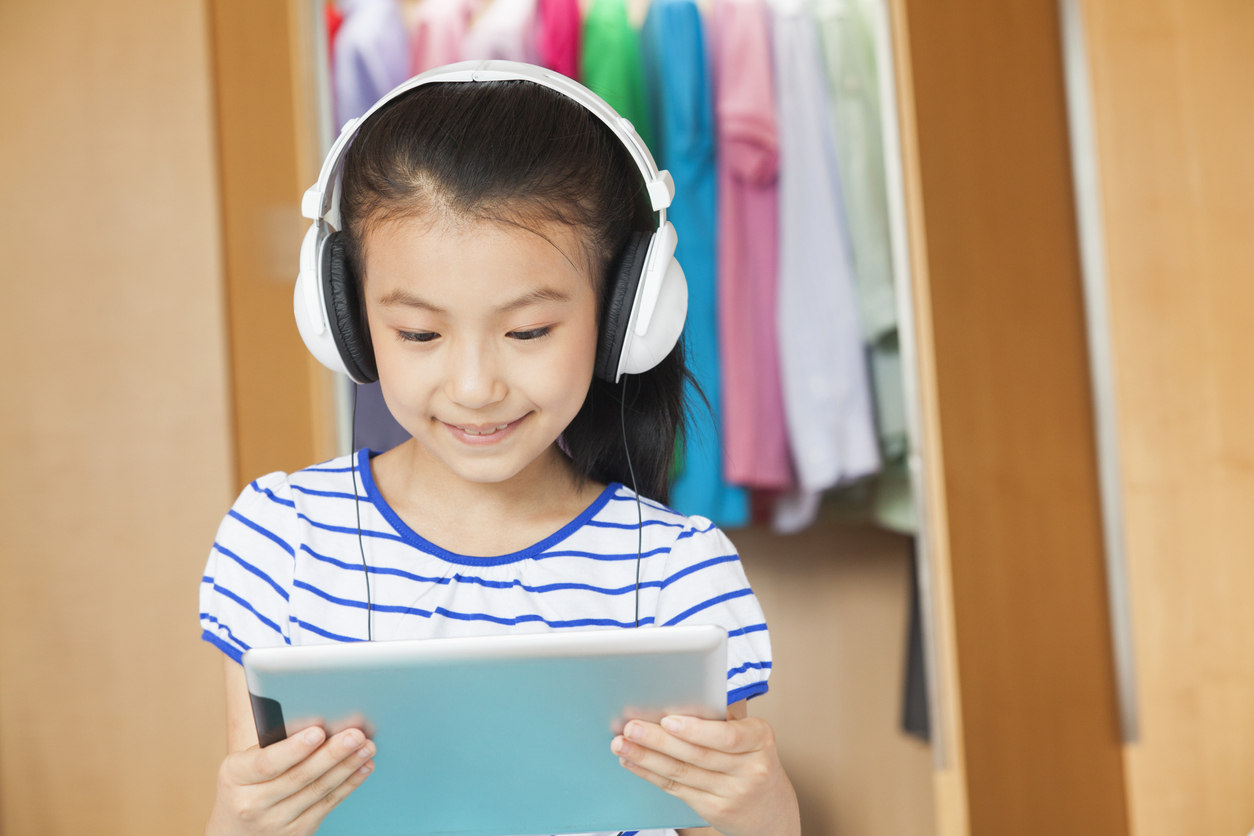 Young girl wearing headphones and viewing content on a tablet computer
