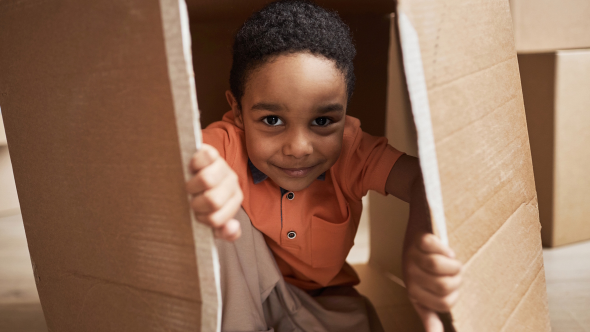 little boy playing in a cardboard box