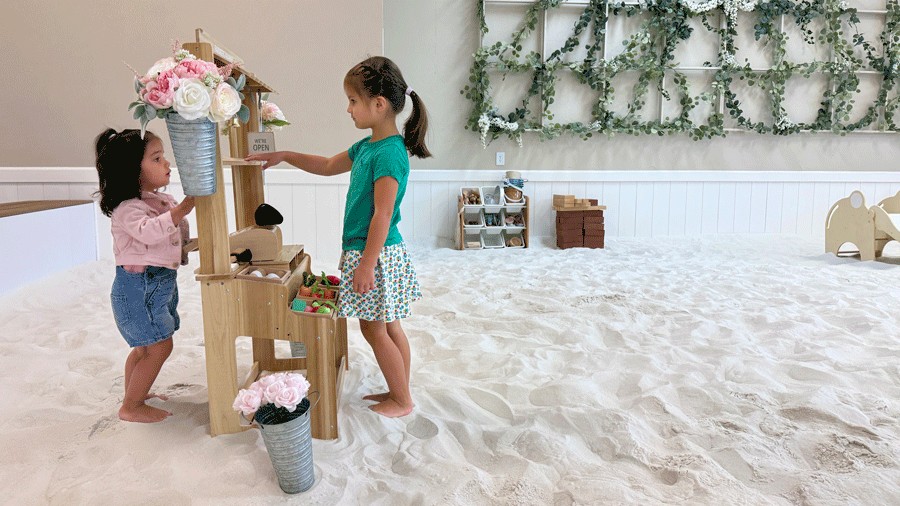 little girls pretend playing in sandbox at the sand garden