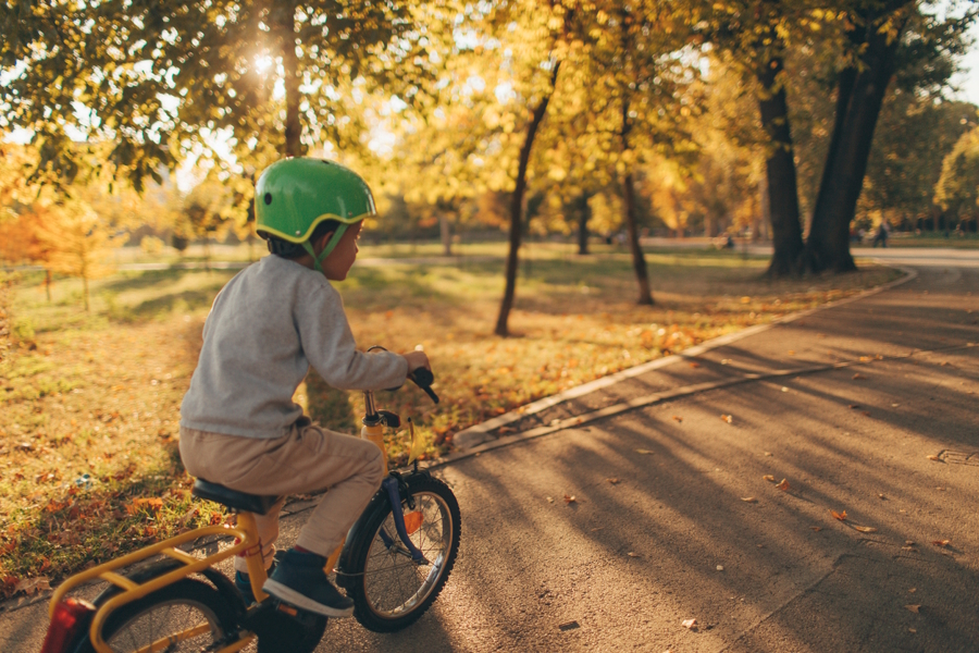 boy on a bike ride on a path in a park in the fall