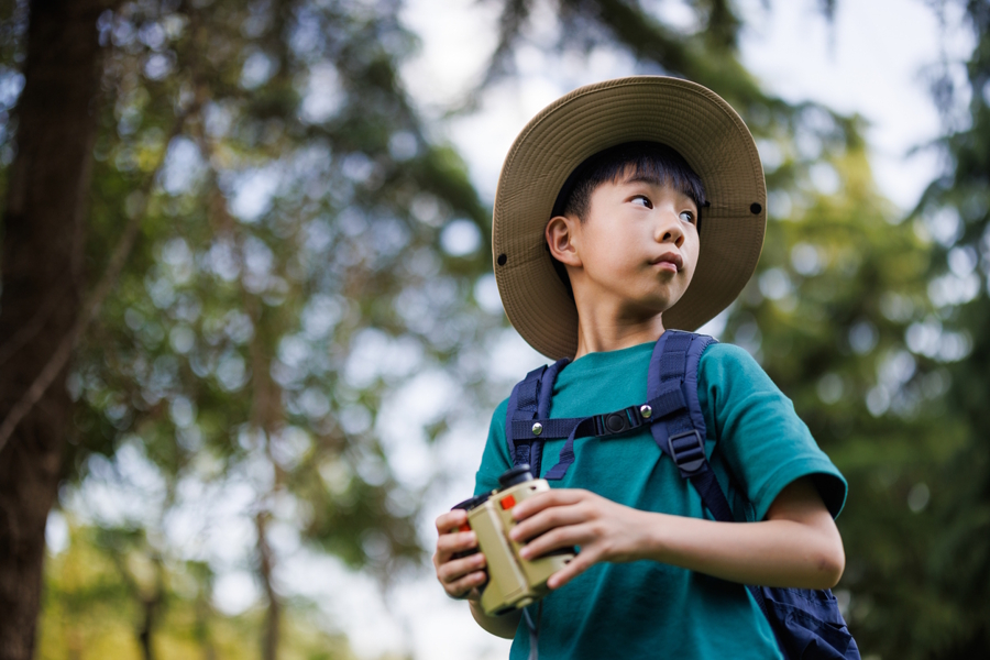 Young boy wearing a sun hat on a hiking looking behind himself