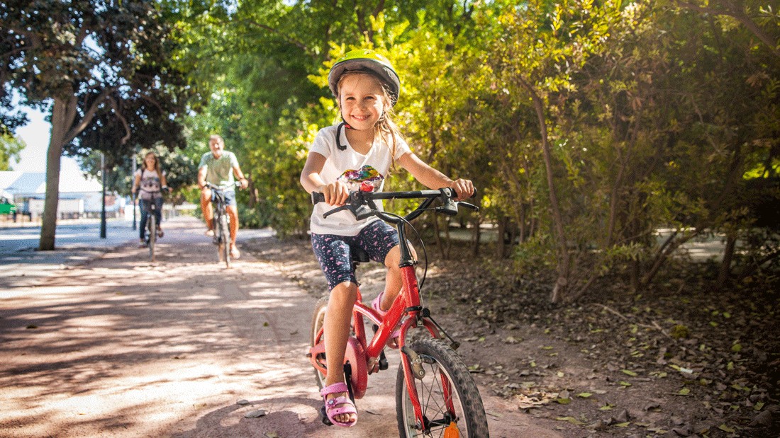 family riding bikes on a paved path on a sunny day in Orting