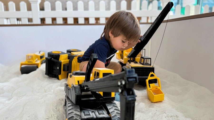young boy with Tonka trucks playing in the indoor sandbox at The Sand Garden