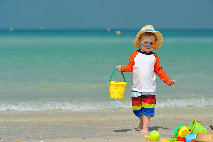 Little boy with a sunhat and sunglasses on the beach on a sunny day
