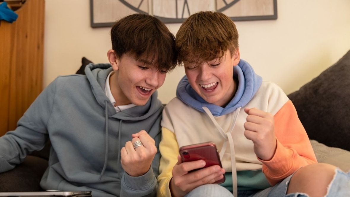 Two teenage boys playing and gambling on smart phones