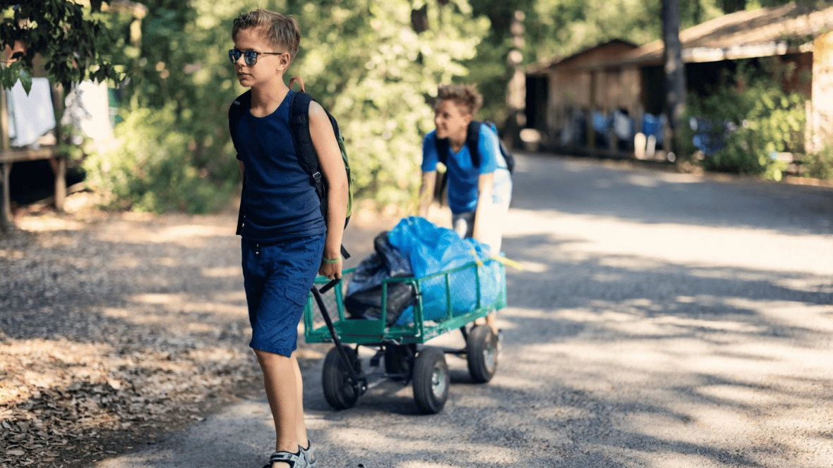 Boys at summer camp with luggage trolley heading to their cabin