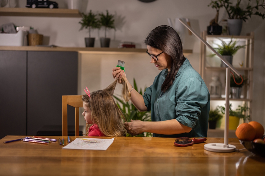 Mom at home treating her daughter for head lice